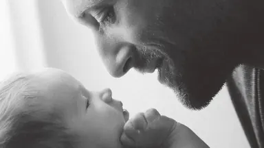 Father and newborn — Photo: Norbert Banhalmi Black and white photograph of a father resting his forehead against his newborn child.