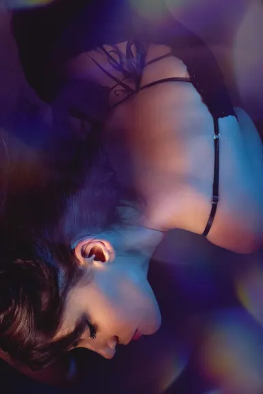 Blue and violet light — Photo: Norbert Banhalmi A woman lies with her head tilted back, lit by blue and violet gels.