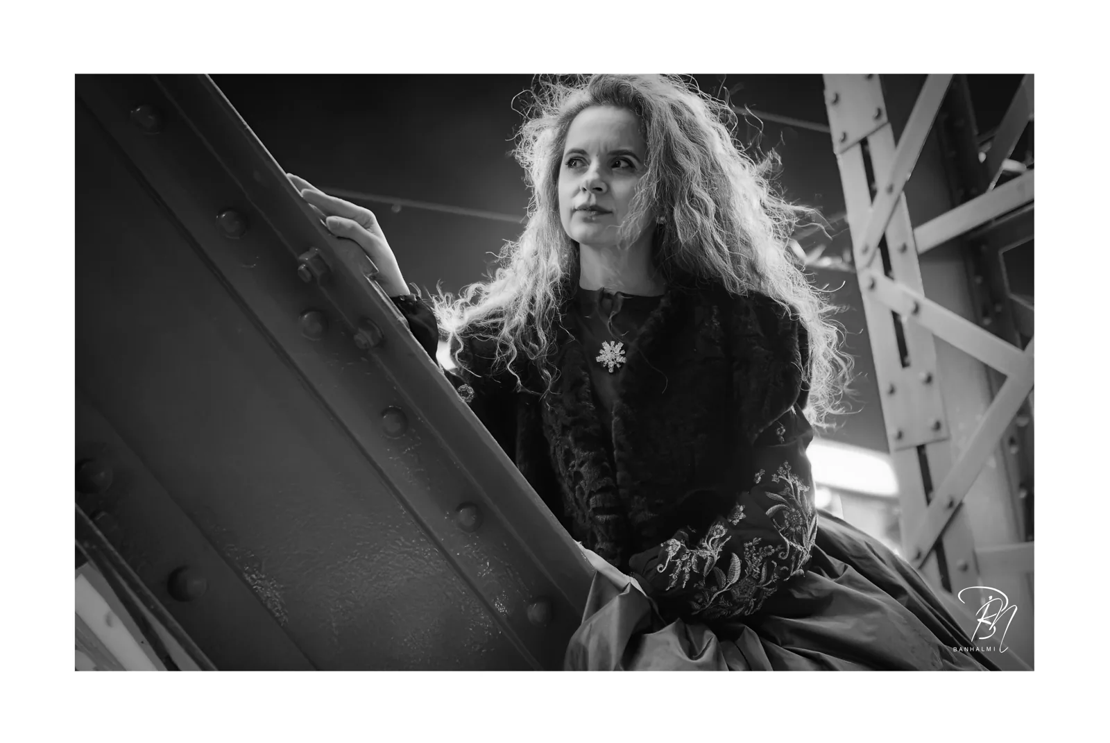 Unter der Eisenbrücke — Foto: Norbert Banhalmi Eine Frau im historischen Kleid lehnt am genieteten Stahl einer Brücke.