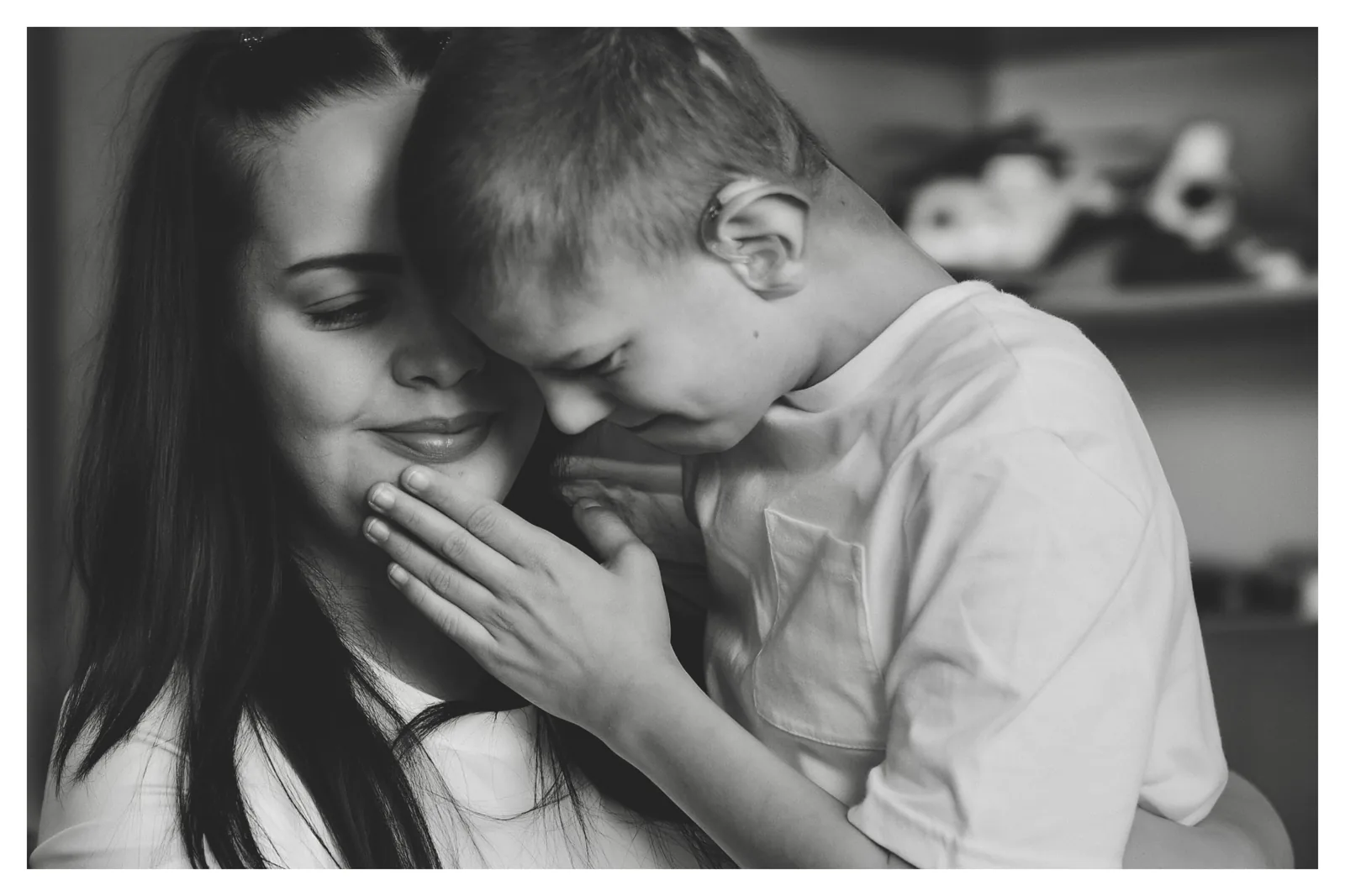 Leaning in — Photo: Norbert Banhalmi A young woman holds a boy who leans into her shoulder, his hands at his face.